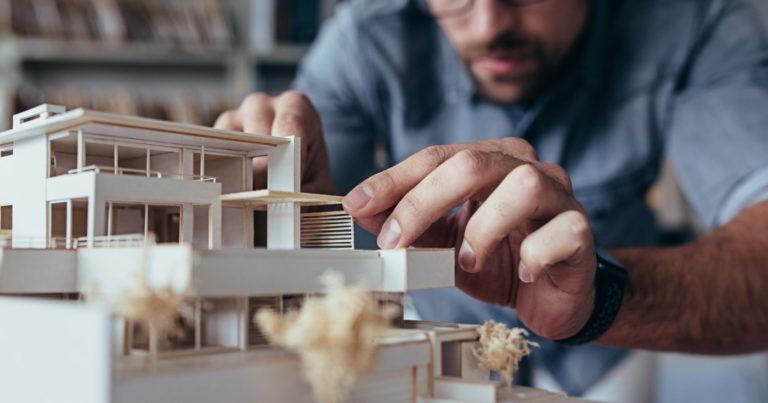Un posible inversor inmobiliario examina los destalles de la maqueta de una casa