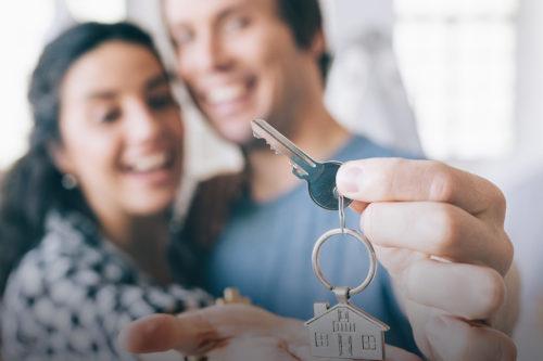 Una pareja sonríe con la llave de su nueva vivienda