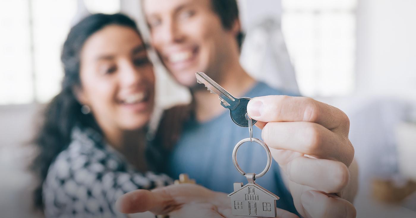 Una pareja sonríe con la llave de su nueva vivienda